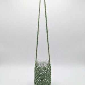 Hanging plant propagation jar with glass container in green crochet holder on white background