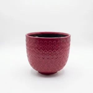 Red pattern ceramic cover pot with embossed geometric design and glossy finish 18cm high by 19cm wide on white background